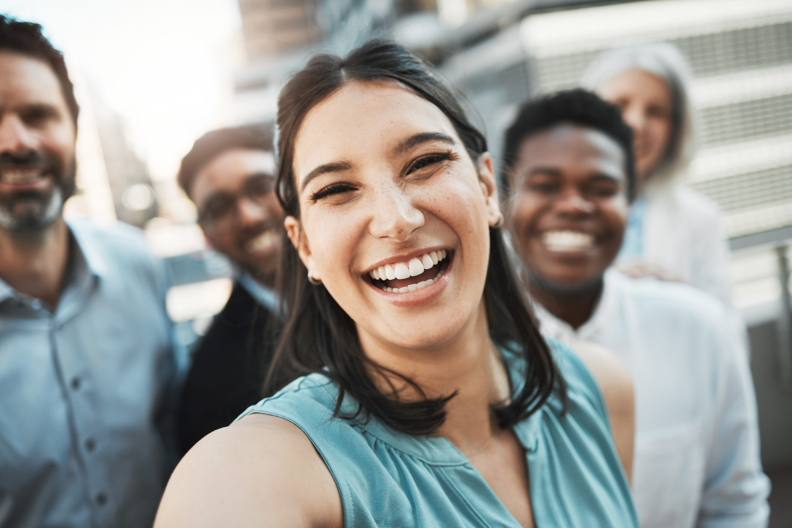 Shot of an attractive young businesswoman standing outside with her colleagues and taking selfies