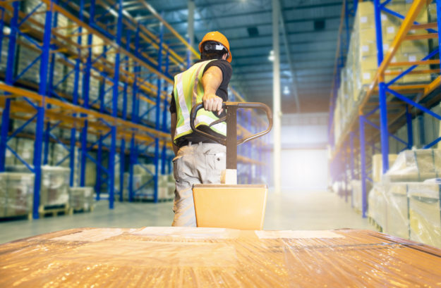 Warehouse worker unloading pallet shipment goods, Interior of storage warehouse,tall shelves storage of goods in warehousing  S