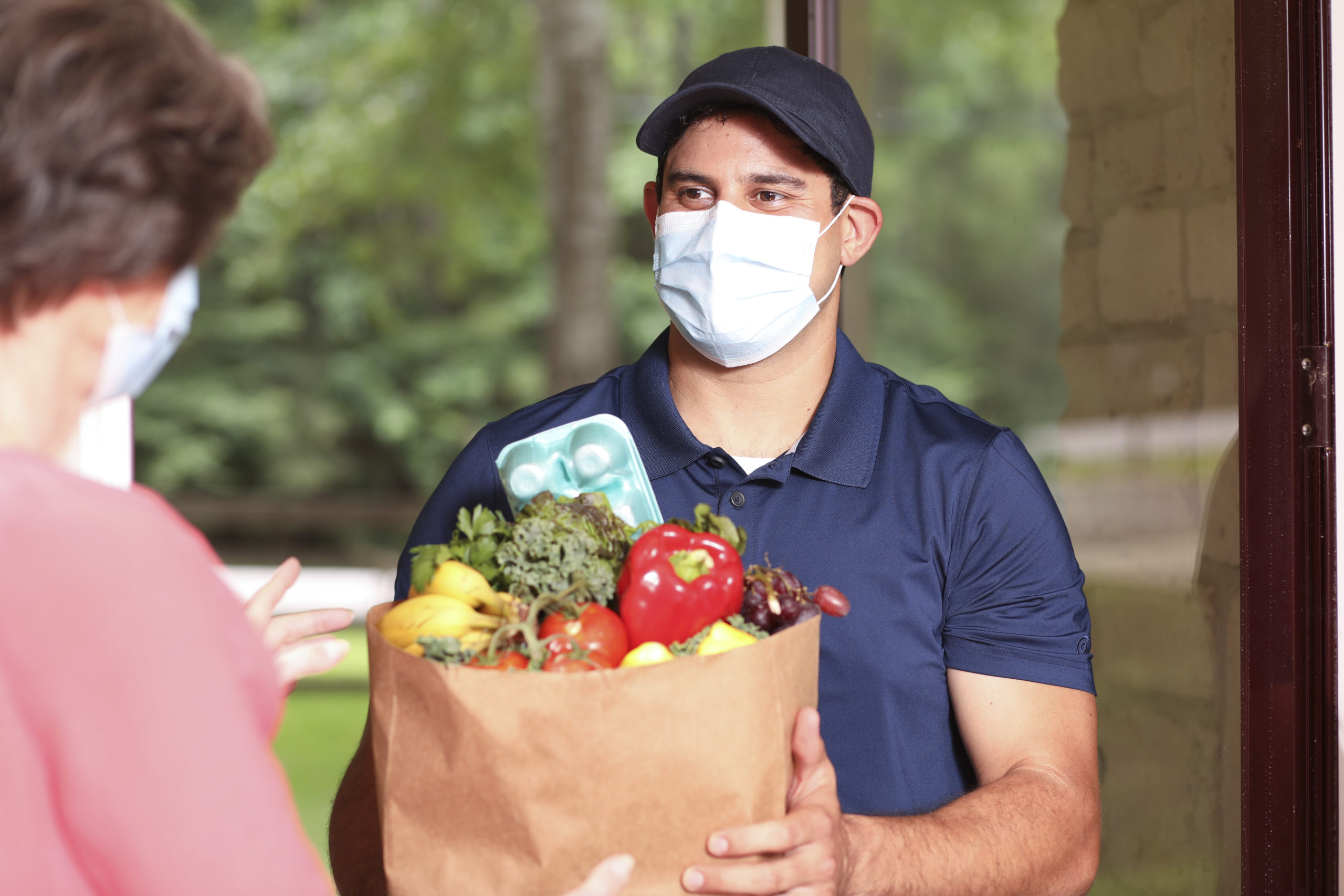 Coronavirus: Man delivers groceries to senior woman at home.