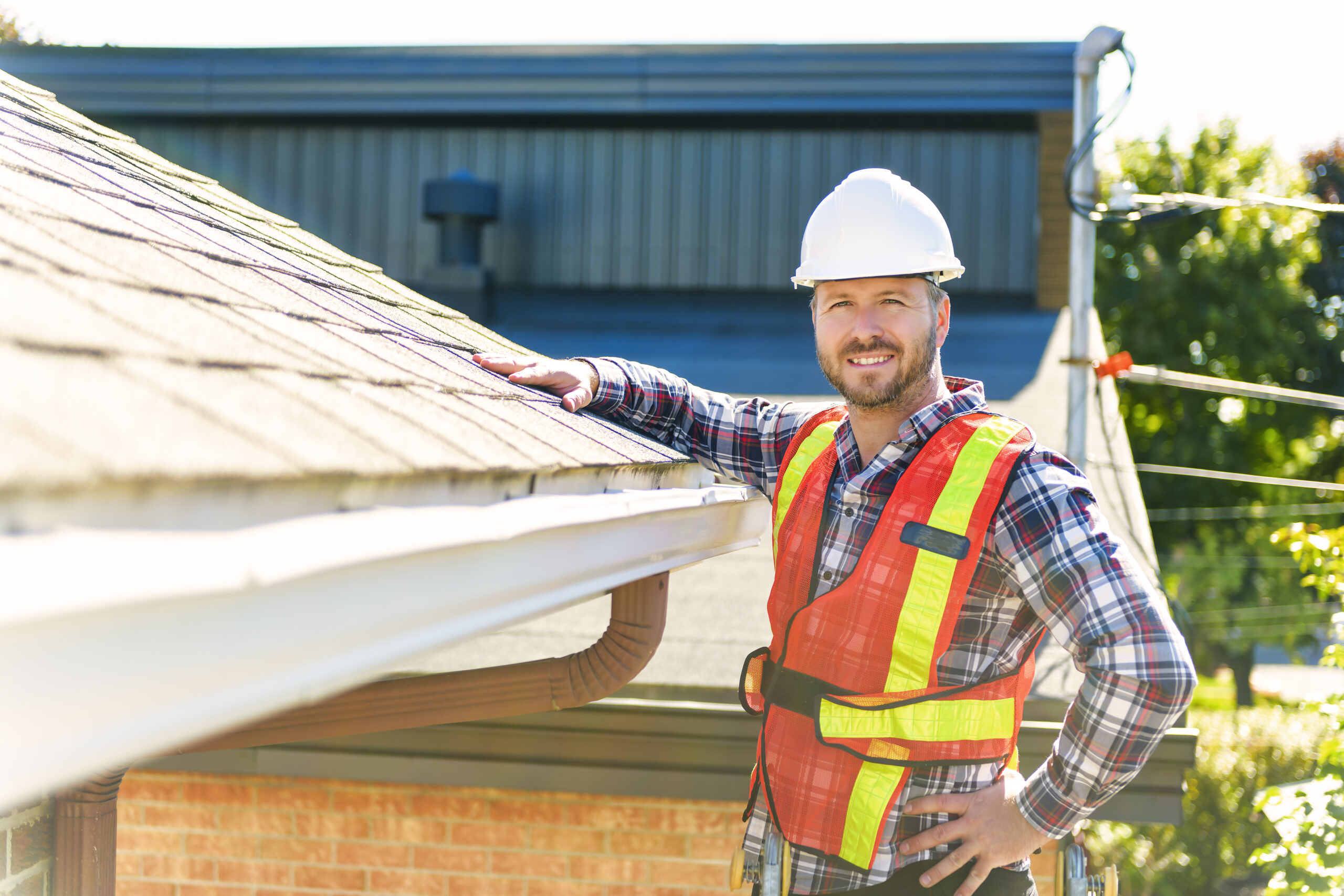man with hard hat standing on steps inspecting house roof