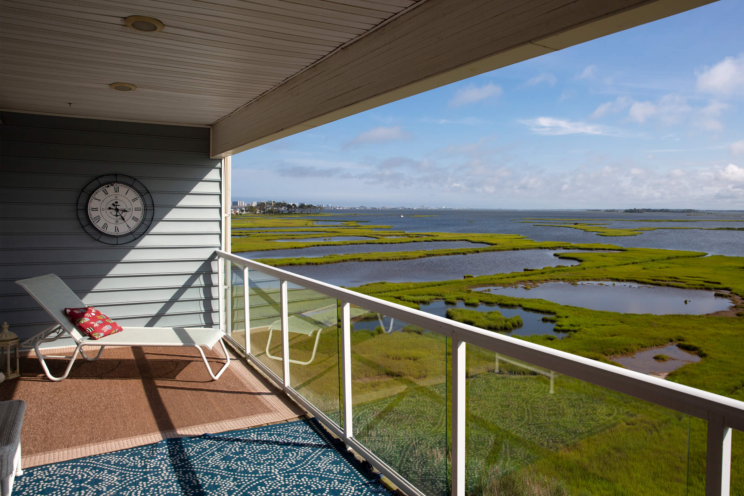 View from balcony of Fenwick Island, DE condominum over marshes of Assawoman Bay with blue skies and Ocean City, MD skyline in the distance.