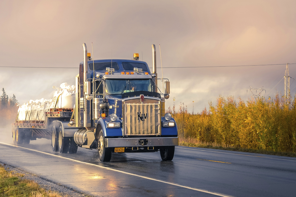 Keep on Truckin Large flatbed semi truck moving freight down the highway on a misty morning.