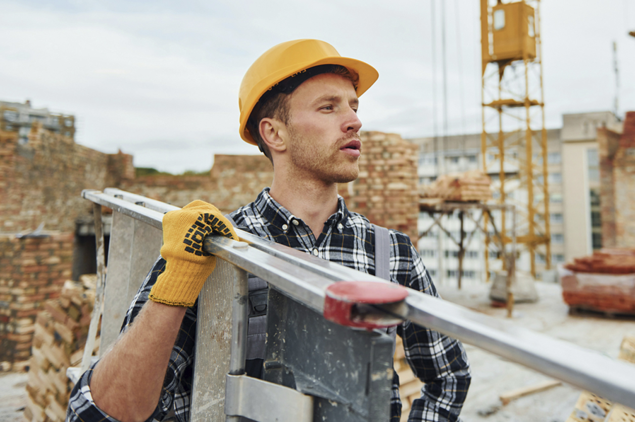 Construction Worker Construction worker in hard hat carrying equipment over his shoulder.
