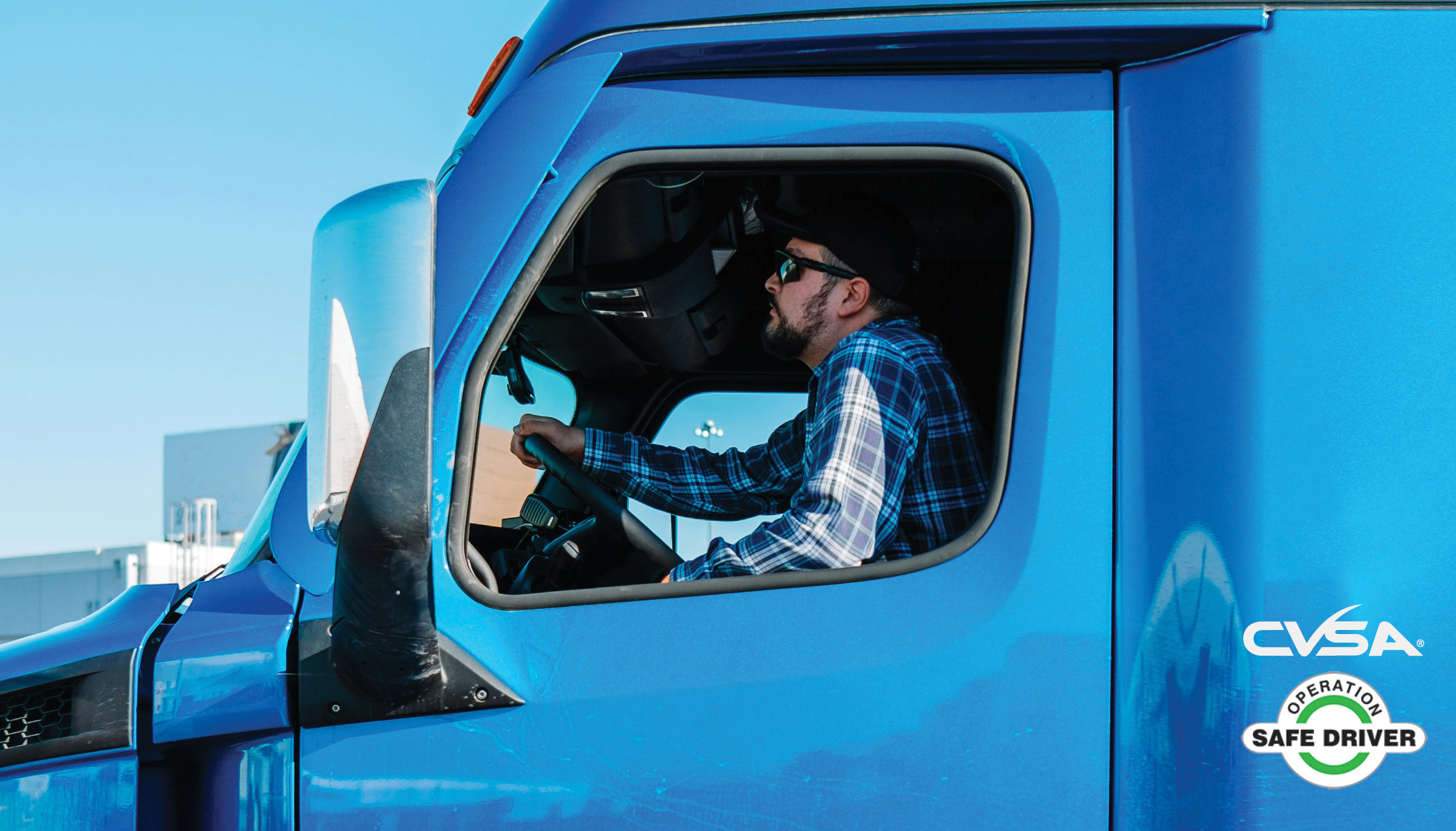 CVSA safe driver Truck driver in blue semi truck cab, looking ahead into traffic.