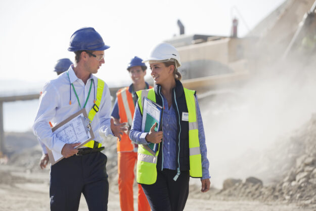 Business people talking in quarry Construction team, architect and insurance professionals consulting on a building site.